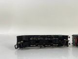 two black trains sitting side by side on a white surface