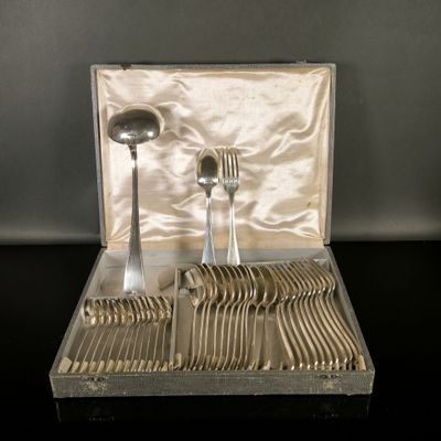 des couverts dans un coffret en argent, posés sur une table avec un fond noir
