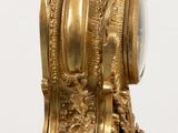 a gold clock sitting on top of a wooden table