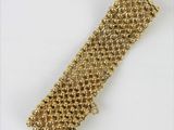 gros plan d'un bracelet en or sur une surface blanche