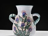 a white vase with blue flowers on it sitting on a table