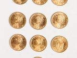 a close up of a number of gold coins on a white surface