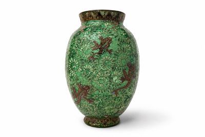 un vase vert posé sur une surface blanche, sur fond blanc