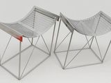 two metal chairs sitting side by side on a white surface