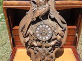 une horloge en bois ornée d'un oiseau, posée dans une boîte