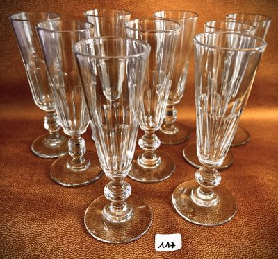 six empty wine glasses are lined up on a brown surface