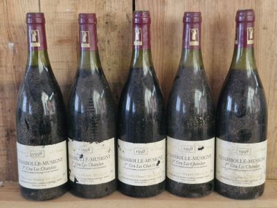 six bottles of wine are lined up on a shelf in front of a wooden wall