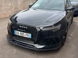 L'Audi noire est garée sur un parking, près d'un mur.