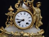 a gold clock with a man and a woman on it