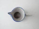 a small blue and white pitcher on a white table
