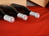 four bottles of wine are lined up on a red table cloth