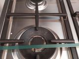 a gas stove with a glass shelf above it