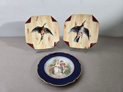 deux assiettes avec des oiseaux peints dessus, posées sur une table