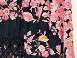 black and pink floral dress hanging on a hanger on a white wall