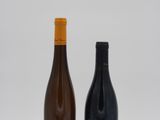 deux bouteilles de vin posées l'une à côté de l'autre sur une surface blanche