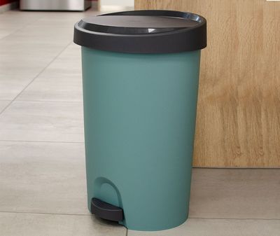 une poubelle bleue posée par terre dans la cuisine