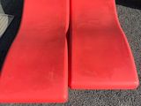 pair of red lounge chairs sitting in front of a glass door