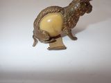 a small statue of a goat with a ball on it ' s back