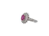 a close up of a diamond and ruby ring on a white background