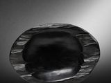 a black and white photo of a glass object on a reflective surface