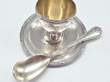 a silver cup and spoon sitting on a silver plate