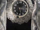 a clock that is sitting on a table with statues around it