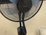 a black fan sitting on top of a table next to a radiator