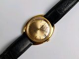 une photo d'une montre-bracelet en or montée sur un bracelet en cuir noir