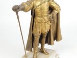 figurine représentant un homme vêtu d'une tenue dorée et tenant une canne