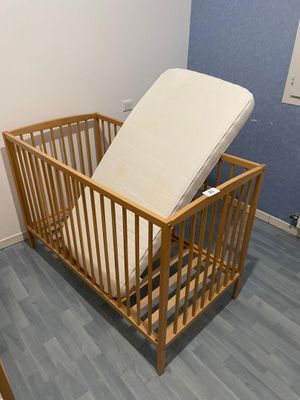 a wooden crib with a mattress on top of it
