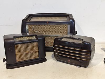 trois vieilles radios posées sur une table à côté d'une paire de ciseaux
