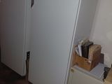 an image of a refrigerator in a room with a lot of clutter on the floor