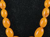 an orange jade bead necklace on a black mannequin