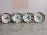 quatre assiettes ornées de motifs floraux sont alignées contre un mur
