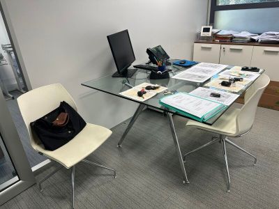 a glass desk with a computer and a laptop on it