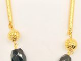 a black and gold necklace with black stones on a gold chain