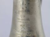 a silver bell with a green top on a white table