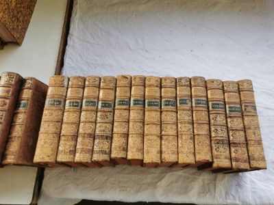 de nombreux vieux livres empilés les uns sur les autres sur un lit