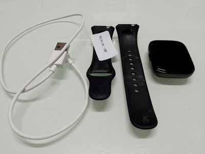 une Apple Watch noire posée à côté d'un chargeur et d'un autre chargeur