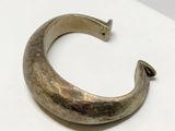 an old silver bracelet with a curved design on a white surface