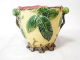 a yellow vase with green leaves on it on a white surface