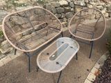 deux chaises en osier et une table basse sur le trottoir