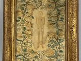 une vieille photo représentant un tableau d'une femme, dans un cadre à motifs floraux