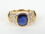 a close up of a gold ring with a blue sapphire and diamonds