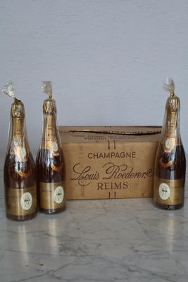 four bottles of champagne in front of a cardboard box on a table