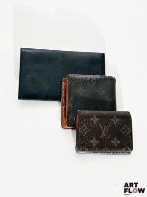 trois portefeuilles Louis Vuitton posés les uns à côté des autres sur une surface blanche