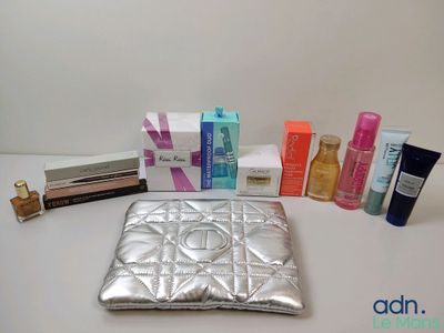 a silver purse sitting on top of a table next to a bunch of cosmetics