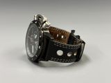 the watch is black and has a brown leather band