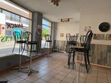 tables and chairs in front of a store window with a clock on the wall