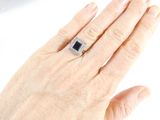 a woman ' s hand holding a black and white diamond ring